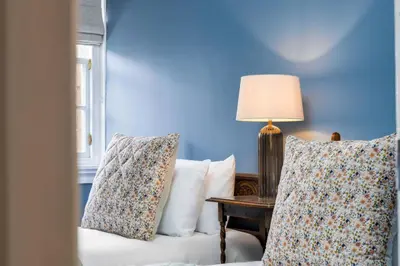 a blue room with a couch and a table with pillows at Elegant 3 Bed Apartment in Stirling Near Free Parking and Hill Views in Stirling