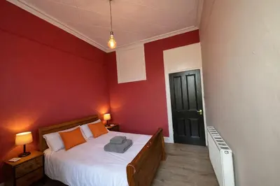 a bedroom with a bed and a red wall at Contractors and Guests Grand 3 Bedroom Central Free Parking Fully equipped in Glasgow