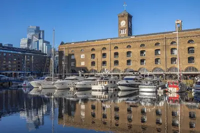 a group of boats docked in front of a building with a clock tower at New! Modern Wapping 1BR Flat near Tower Bridge in Moffat