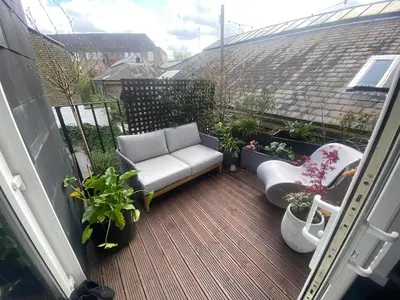 a balcony with a couch and chairs and plants at Central London stylish 2-Bed House, with 2 terraces in Moffat