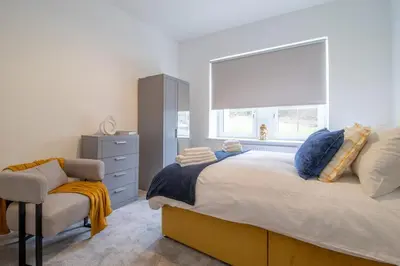 a bedroom with a bed and a chair and a window at William Wallace View - 5 Bedrooms in Stirling in Stirling
