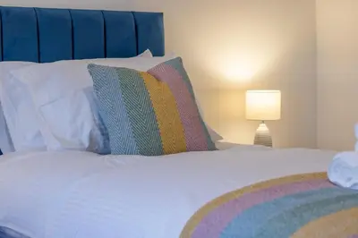a white bed with a colorful pillow and a lamp at William Wallace View - 5 Bedrooms in Stirling in Stirling