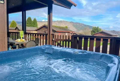 a jacuzzi tub on the deck of a house at Heather Lodge with Hot Tub in Hunters Quay