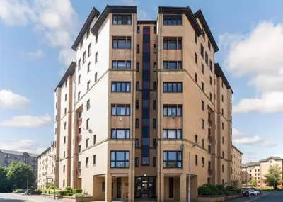 a tall brick building on a city street at Stylish 2 Bed Duplex with Balcony & Parking Merchant City in Glasgow