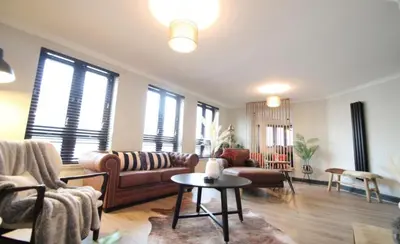 a living room with a couch and a table at Stylish 2 Bed Duplex with Balcony & Parking Merchant City in Glasgow