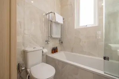 a bathroom with a toilet and a tub and a sink at Barnton Grove Getaway in Edinburgh