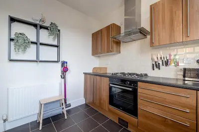 a kitchen with wooden cabinets and a stove top oven at Barnton Grove Getaway in Edinburgh
