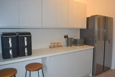 a kitchen with a counter with two stools and a refrigerator at Large 8 Bed Group and Contractor Accommodation in Stirling