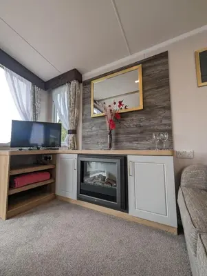 a living room with a fireplace and a tv at Swift Bordeaux Sea View No 2 in Dunoon