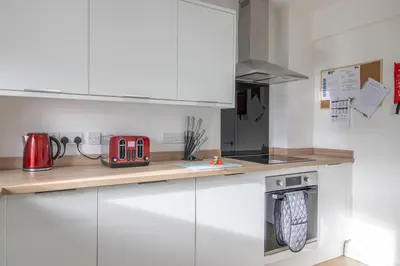 a kitchen with white cabinets and a red appliance at Betty's House - 3 bedroom in Coatbridge in Glenboig