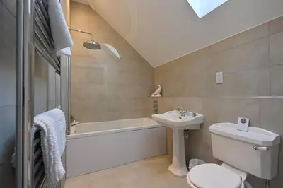 a bathroom with a sink and a toilet and a bath tub at Kennels Cottage in Buchanty