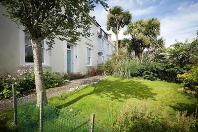 a white house with a yard with palm trees at 25 Ardbeg Road in Rothesay
