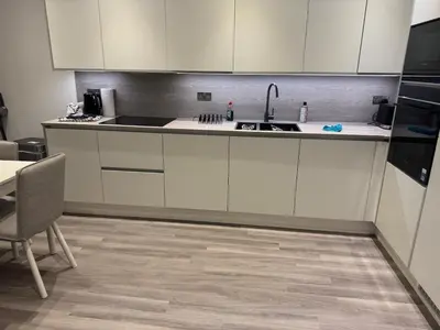 a kitchen with white cabinets and a sink and a table at Colindale Condominium in Moffat