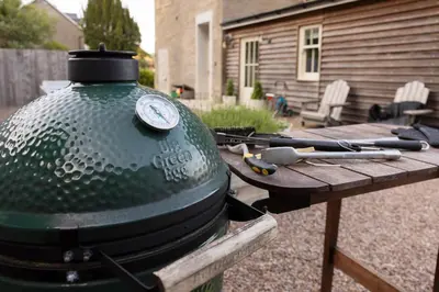 a grill sitting next to a wooden picnic table at The Hollies Argyll in Tighnabruaich