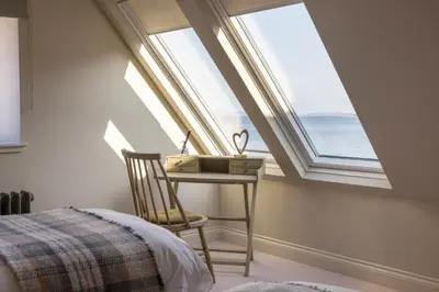 a bedroom with a bed and a desk with a window at The Hollies Argyll in Tighnabruaich