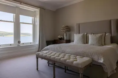 a bedroom with a large bed and a large window at The Hollies Argyll in Tighnabruaich