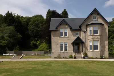 a large brick house with a green lawn at The Hollies Argyll in Tighnabruaich