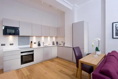 a kitchen and dining room with a purple couch and a table at Destiny Scotland - Princes Street Residence in Edinburgh