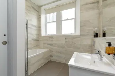 a bathroom with a tub and a sink and a window at Destiny Scotland - Princes Street Residence in Edinburgh