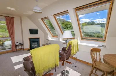 a living room with a table and chairs and windows at Blarghour Farm Cottages in Ardchonnell
