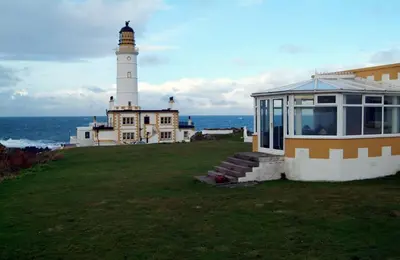 a lighthouse on top of a building with a house at Corsewall Lighthouse Hotel in Kirkcolm