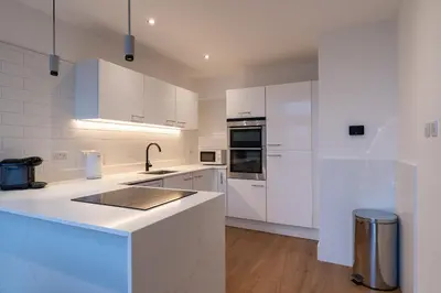 a white kitchen with white cabinets and a sink at CITY CENTRE APARTMENT with Free Secure Underground Parking in Glasgow