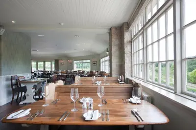 a restaurant with wooden tables and chairs and windows at The Bridge Inn in Ratho