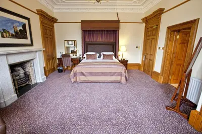 a bedroom with a bed and a fireplace at The Grange Manor in Grangemouth