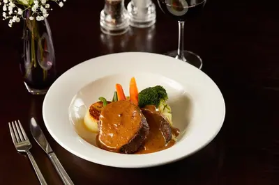 a plate of food with meat and vegetables on a table at The Grange Manor in Grangemouth