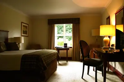 a hotel room with a bed and a desk and a window at The Grange Manor in Grangemouth