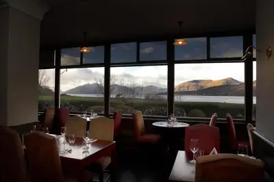 a restaurant with tables and chairs and a large window at The Ballachulish Hotel in Glencoe