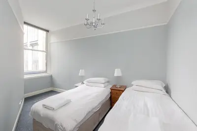 two beds in a white room with a window at Rose Street Residence in Edinburgh