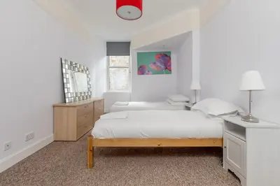 a white bedroom with a bed and a desk at Rose Street Residence in Edinburgh