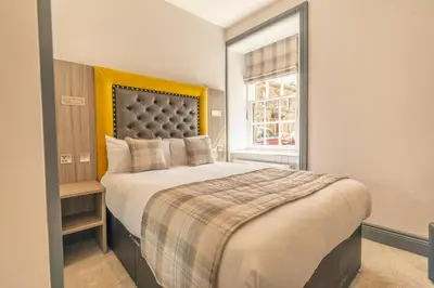 a bedroom with a large bed and a window at Court Residence Aparthotel in Linlithgow