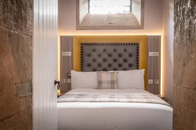 a bedroom with a bed with a large headboard at Court Residence Aparthotel in Linlithgow