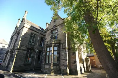 an old stone building with a tree in front of it at Court Residence Aparthotel in Linlithgow