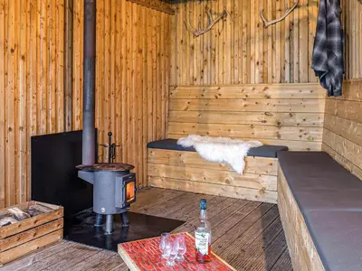a wooden cabin with a wood stove and a table at Carsaig in Port of Menteith