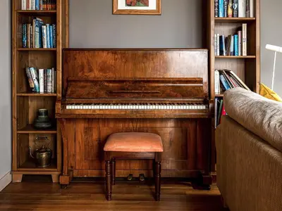 an old piano with a stool next to a book shelf at Carsaig in Port of Menteith