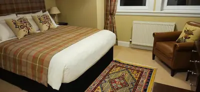 a hotel room with a bed and a chair at Butt Lodge in Lochranza