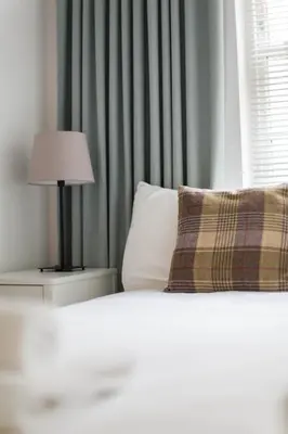 a bedroom with a bed with a lamp and a window at Modern Grassmarket Apartment in Edinburgh
