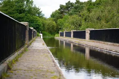 a canal with a fence next to a body of water at Linwater Caravan Park - Luxury Lodges and Static Caravans near Edinburgh in Newbridge