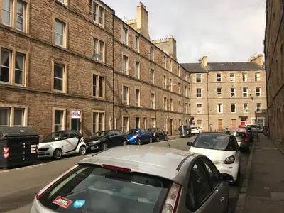 a row of cars parked on a street with buildings at Edinburgh Central Apartment in Edinburgh