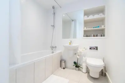 a white bathroom with a tub and a toilet at Mitchell Street Glasgow Apartment in Glasgow
