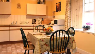a kitchen with a table with a bowl of fruit on it at Inverawe Cottages in Taynuilt