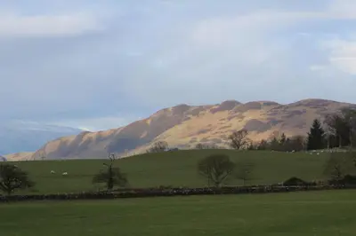 a green field with mountains in the background at Shandon Farmhouse Bed and Breakfast in Drymen