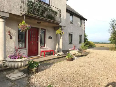 a house with a red door and some potted plants at Shandon Farmhouse Bed and Breakfast in Drymen