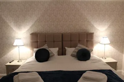 a bedroom with a large bed with two lamps at Shandon Farmhouse Bed and Breakfast in Drymen