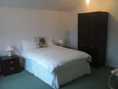 a bedroom with a white bed and a black cabinet at Lochgair Hotel in Lochgair