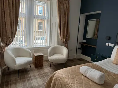 a bedroom with two chairs and a bed and a window at Sandvilla Guesthouse in Oban