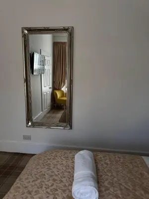 a mirror on a wall next to a bed in a room at Sandvilla Guesthouse in Oban
